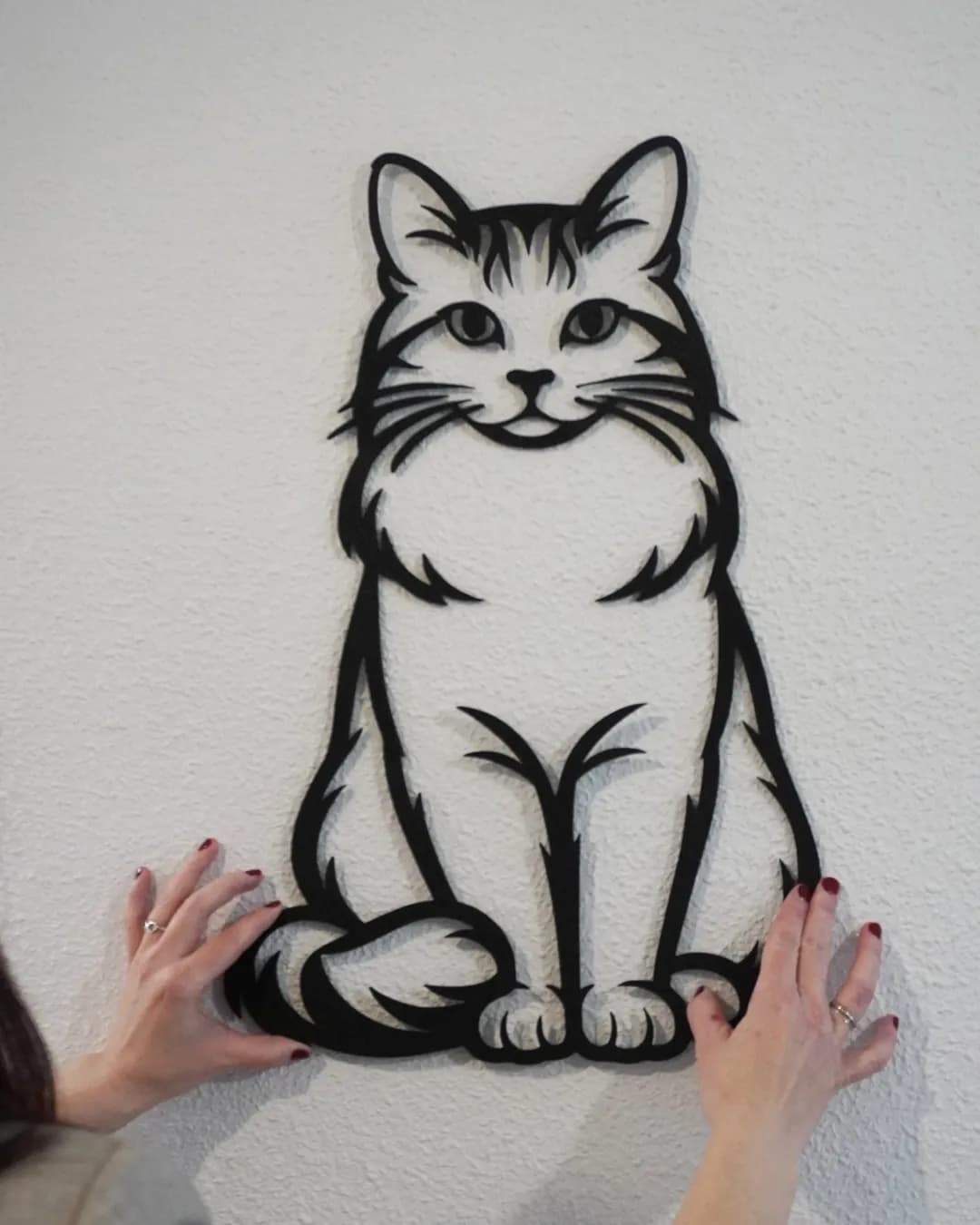 El gato impreso en 3D colgado en una pared blanca, foto real sin retoque